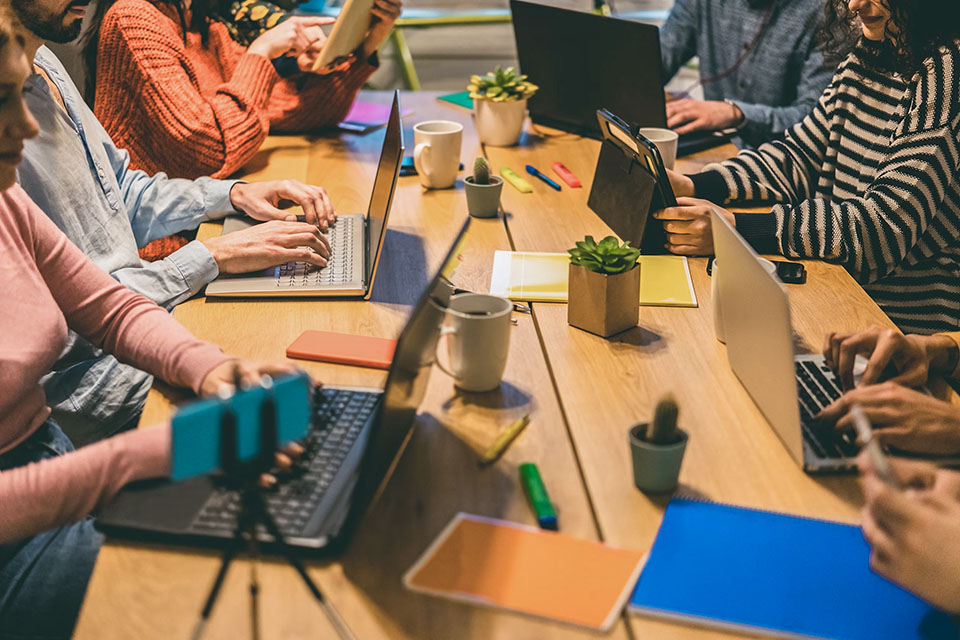 Group of professionals using laptops and devices at a shared workspace table powered by Kinetic Business Fiber Internet