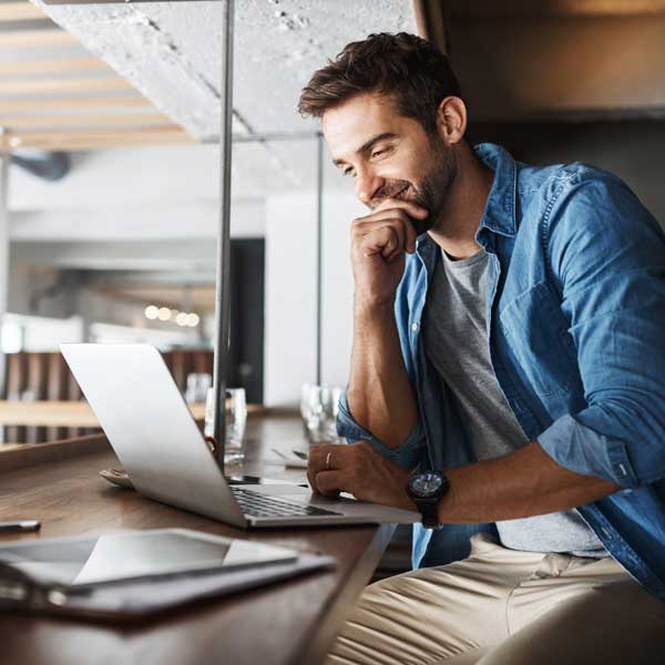 young-man-blue-denim-shirt-laptop-coworking-smiling